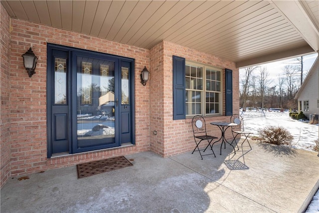 snow covered property entrance with covered porch