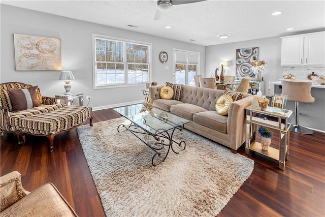 living room featuring dark wood-type flooring, ceiling fan, and a textured ceiling