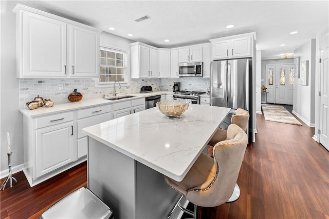 kitchen with sink, a breakfast bar area, appliances with stainless steel finishes, a kitchen island, and white cabinets