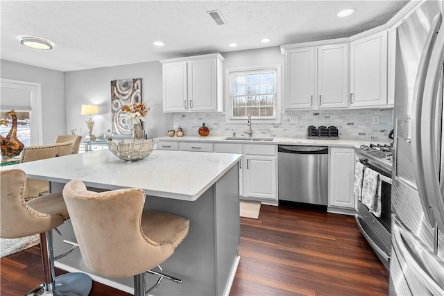 kitchen featuring white cabinetry, appliances with stainless steel finishes, sink, and a breakfast bar area