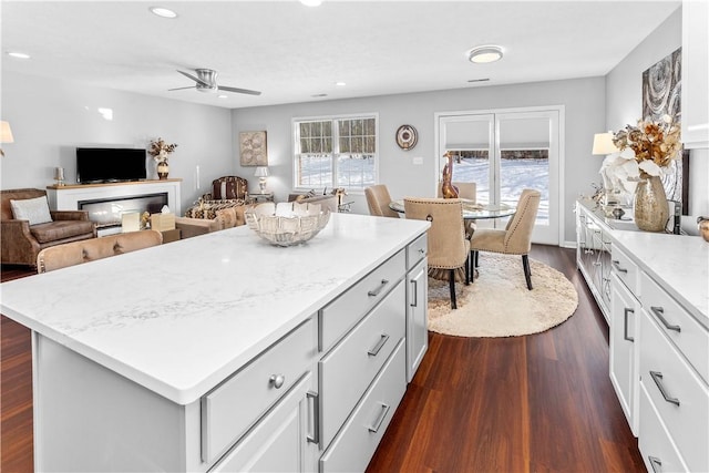 kitchen with dark hardwood / wood-style flooring, plenty of natural light, white cabinets, and a kitchen island