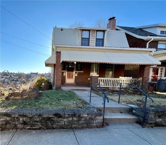 view of front of property featuring metal roof, a porch, and brick siding