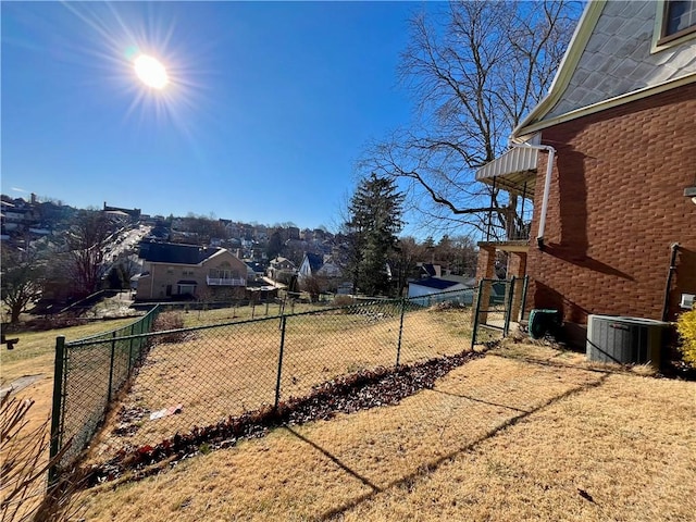 view of yard featuring a residential view, central AC, and fence