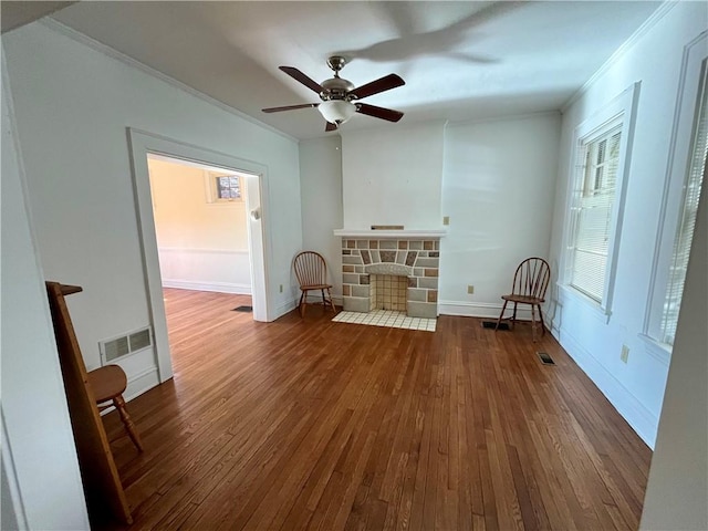 interior space with ornamental molding, dark hardwood / wood-style floors, ceiling fan, and a fireplace