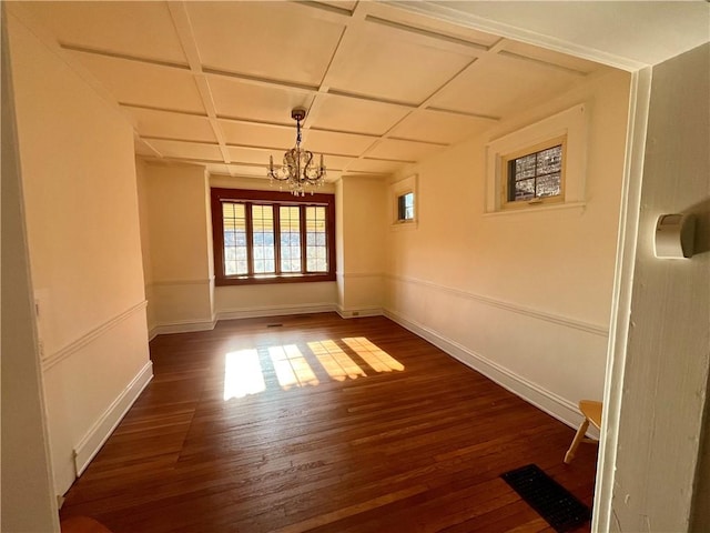 empty room with coffered ceiling, a notable chandelier, and dark hardwood / wood-style floors