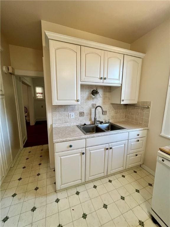 kitchen with white dishwasher, sink, tasteful backsplash, and white cabinets