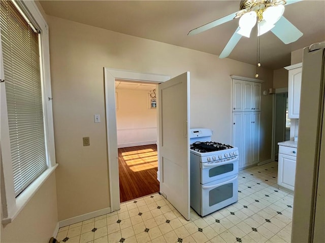 kitchen with range with two ovens, white cabinets, and ceiling fan