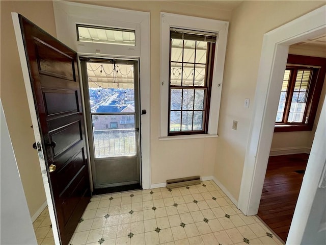 doorway with baseboards, light floors, and a healthy amount of sunlight