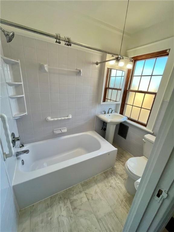 full bath with a sink, toilet, tile walls, and shower / tub combination