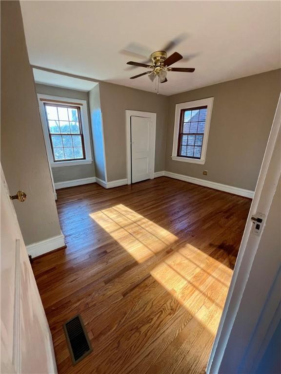 unfurnished bedroom with a ceiling fan, wood finished floors, visible vents, and baseboards