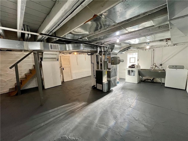 basement featuring heating unit, sink, and washer and dryer