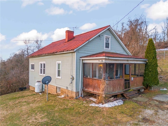 back of property featuring a sunroom and a lawn