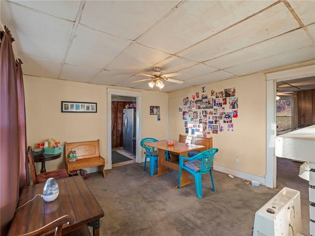 carpeted dining area featuring ceiling fan and a paneled ceiling