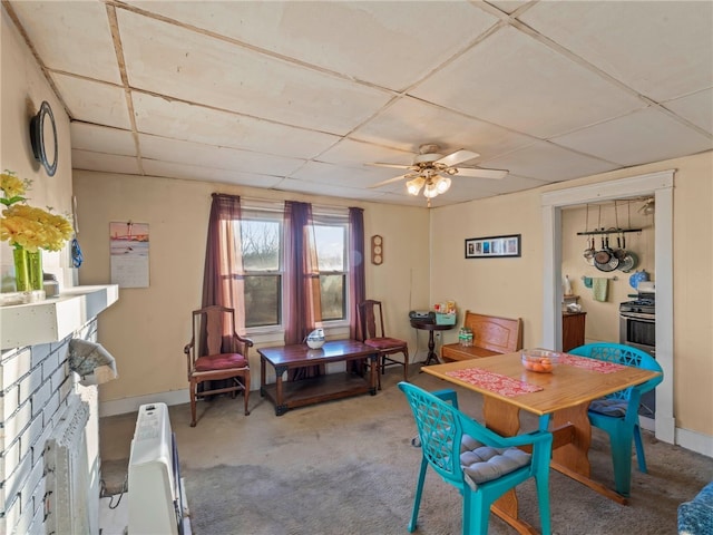 carpeted dining room with ceiling fan, a paneled ceiling, a fireplace, and heating unit