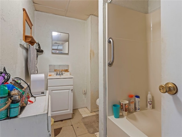 bathroom featuring vanity, toilet, and a drop ceiling