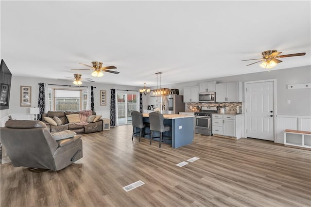 living room with wood-type flooring and ceiling fan with notable chandelier