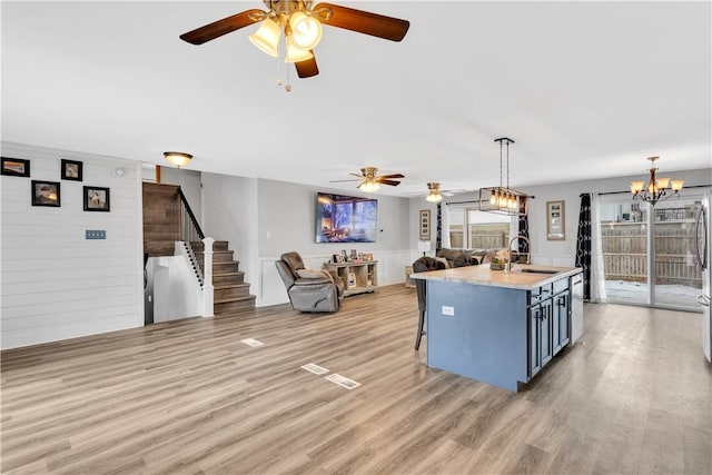 kitchen featuring sink, decorative light fixtures, a chandelier, a kitchen breakfast bar, and a kitchen island with sink