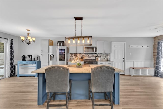 kitchen with stainless steel appliances, a breakfast bar, light wood-type flooring, and decorative light fixtures