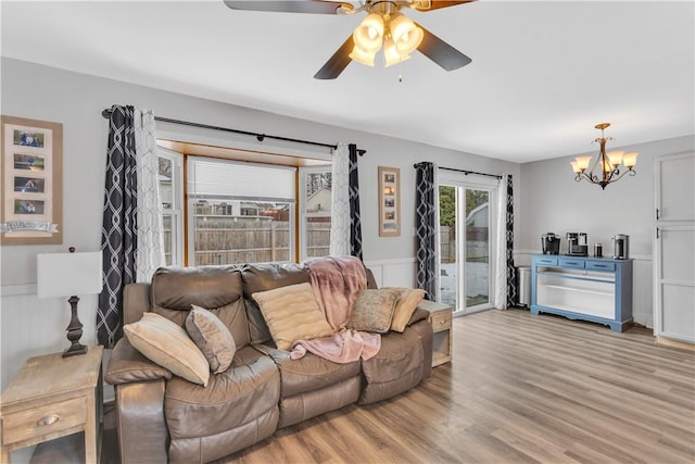 living room featuring ceiling fan with notable chandelier and light hardwood / wood-style flooring