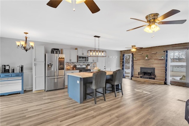 kitchen featuring stainless steel appliances, a kitchen breakfast bar, a kitchen island, decorative light fixtures, and a wood stove