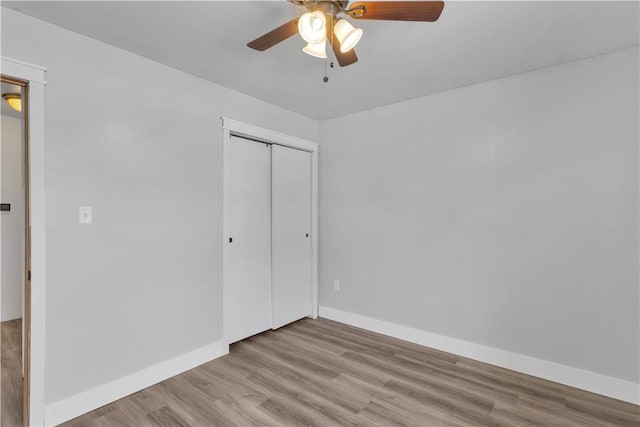 unfurnished bedroom featuring ceiling fan, light hardwood / wood-style floors, and a closet