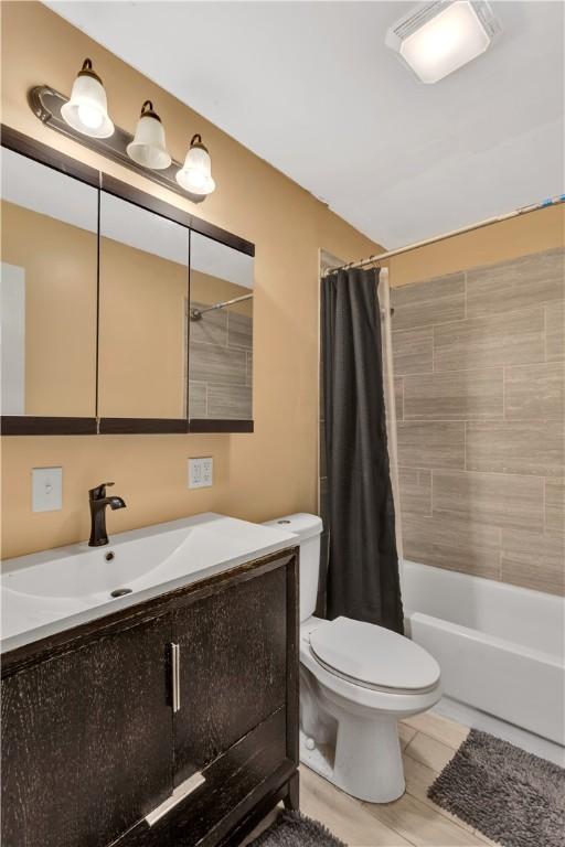 full bathroom featuring shower / tub combo with curtain, vanity, and toilet