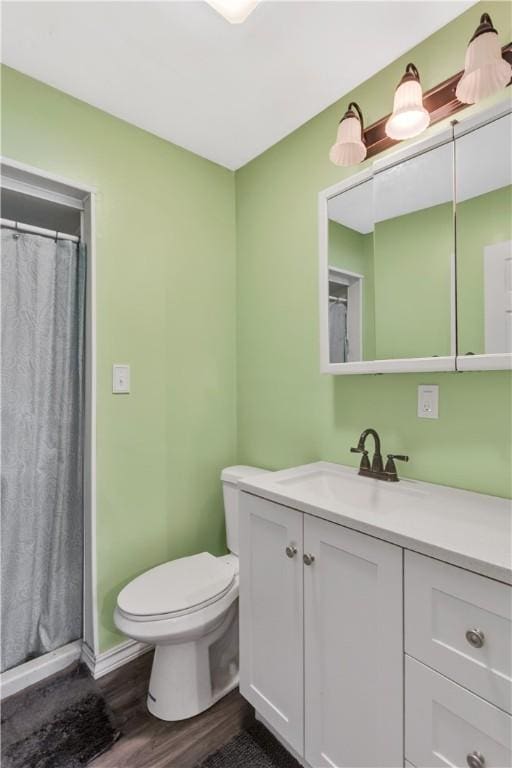 bathroom featuring hardwood / wood-style flooring, vanity, curtained shower, and toilet