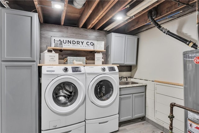 clothes washing area with cabinets, sink, wooden walls, and washer and clothes dryer