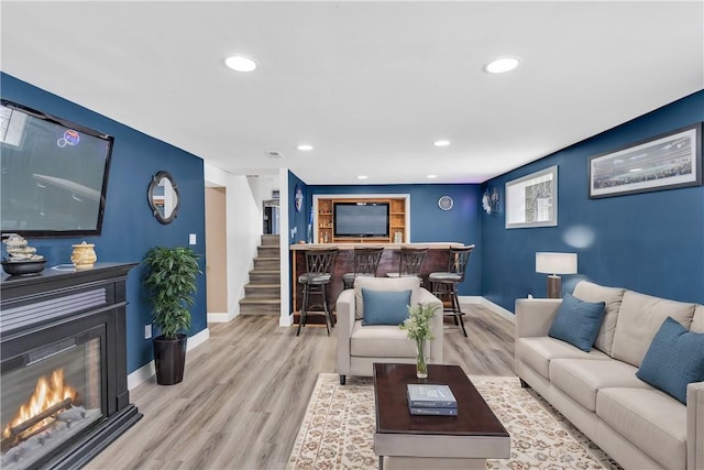 living room with indoor bar and light hardwood / wood-style flooring