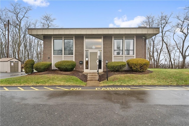 view of front of home with a storage unit and a front lawn