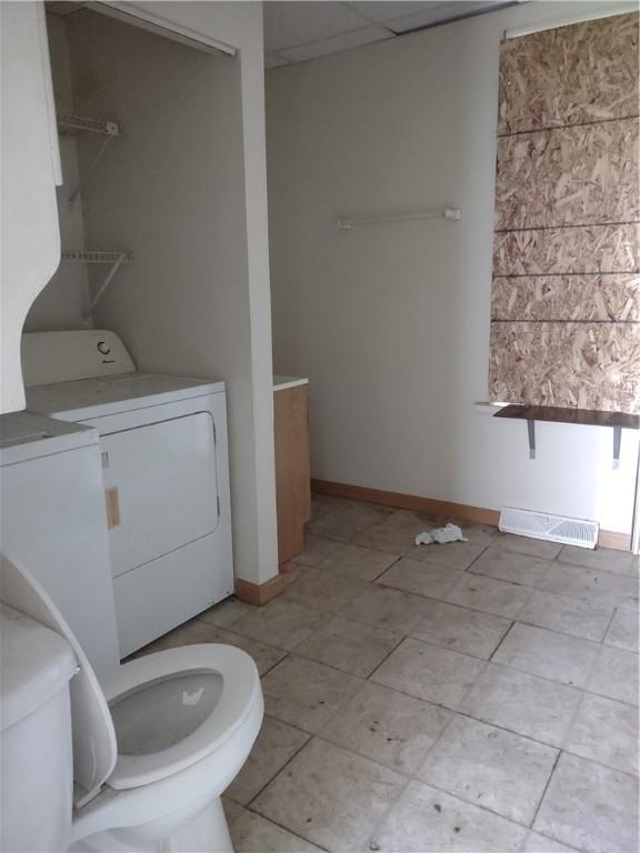 bathroom featuring a drop ceiling, tile patterned flooring, independent washer and dryer, and toilet