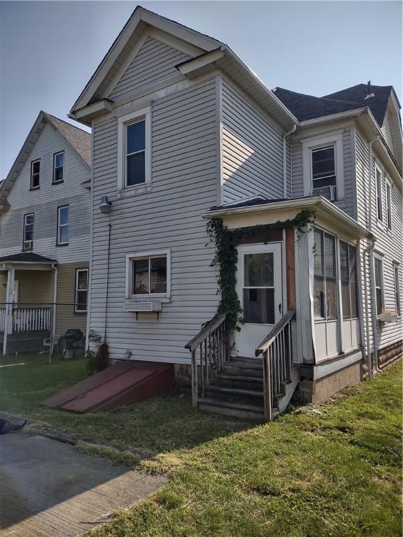 back of property featuring a yard and a sunroom