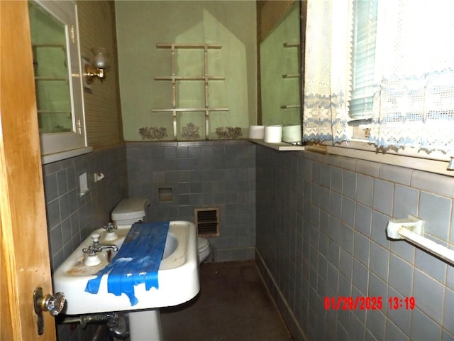 bathroom with tile walls, sink, and toilet