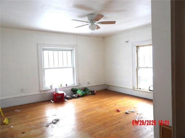 empty room with ceiling fan, a healthy amount of sunlight, and wood-type flooring