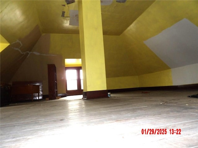 additional living space with wood-type flooring and vaulted ceiling