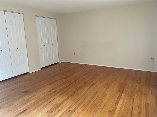 unfurnished bedroom with multiple closets and hardwood / wood-style floors