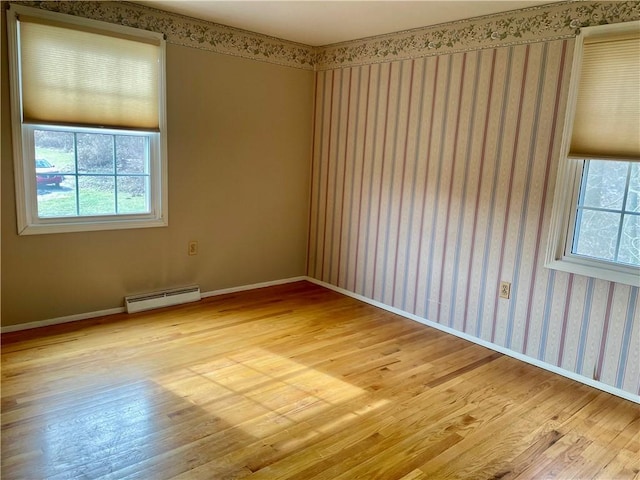 unfurnished room featuring light hardwood / wood-style floors and a baseboard heating unit