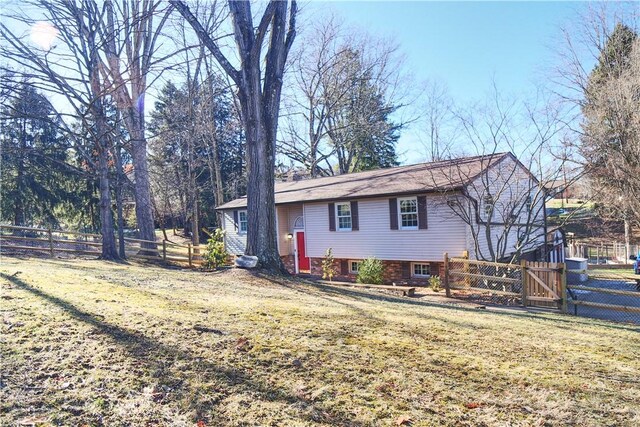 back of property featuring a gate, fence, and a yard