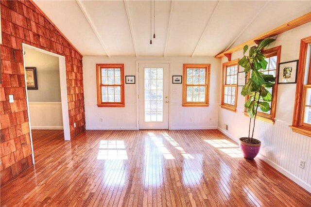 interior space with vaulted ceiling with beams, wood-type flooring, and baseboards