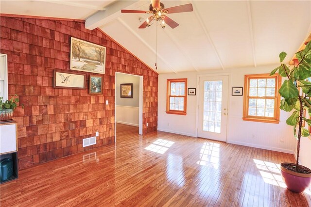 interior space featuring vaulted ceiling with beams, ceiling fan, visible vents, baseboards, and wood-type flooring