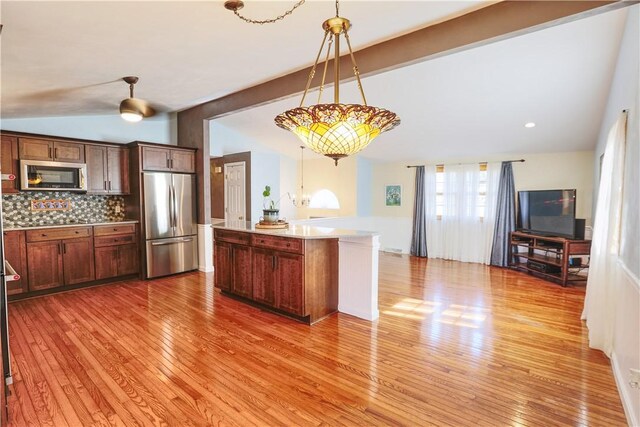 kitchen featuring vaulted ceiling with beams, light wood finished floors, tasteful backsplash, light countertops, and appliances with stainless steel finishes