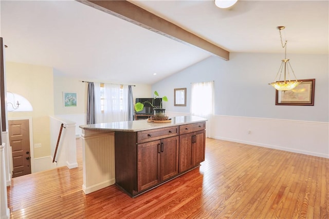 kitchen with a center island, pendant lighting, light wood finished floors, light countertops, and lofted ceiling with beams