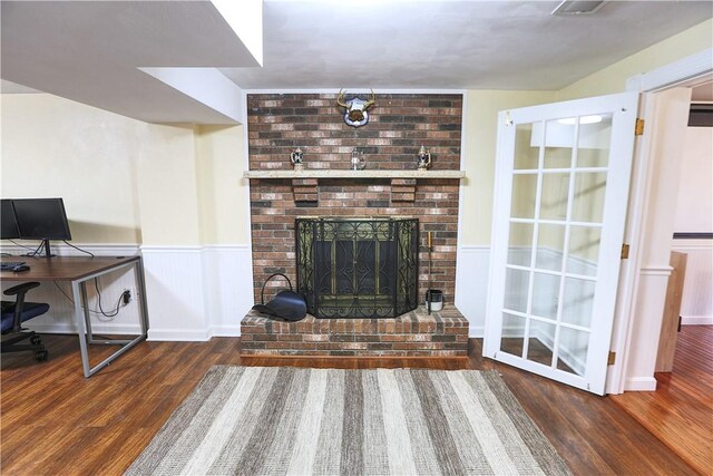 living area featuring a wainscoted wall, a fireplace, and wood finished floors