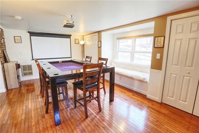 dining area with light wood finished floors and wainscoting