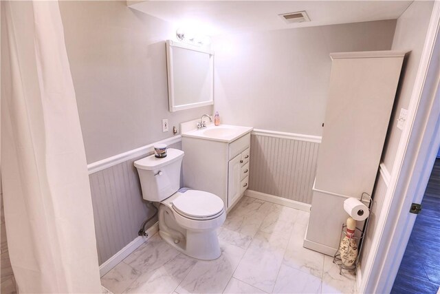 bathroom with marble finish floor, wainscoting, visible vents, and toilet