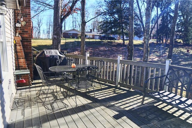 wooden deck featuring outdoor dining area and a grill