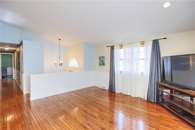 living area with lofted ceiling, hardwood / wood-style floors, visible vents, and a notable chandelier