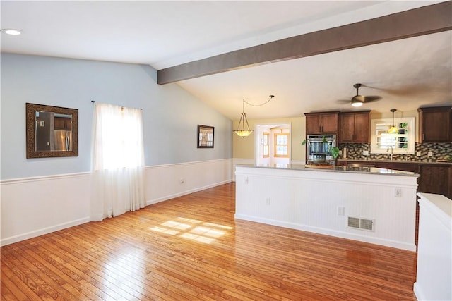 kitchen with a healthy amount of sunlight, light wood-style floors, visible vents, and a wainscoted wall