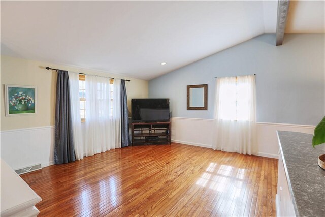 unfurnished living room featuring lofted ceiling, visible vents, and a healthy amount of sunlight