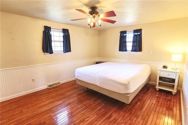 bedroom featuring a wainscoted wall, multiple windows, and hardwood / wood-style flooring